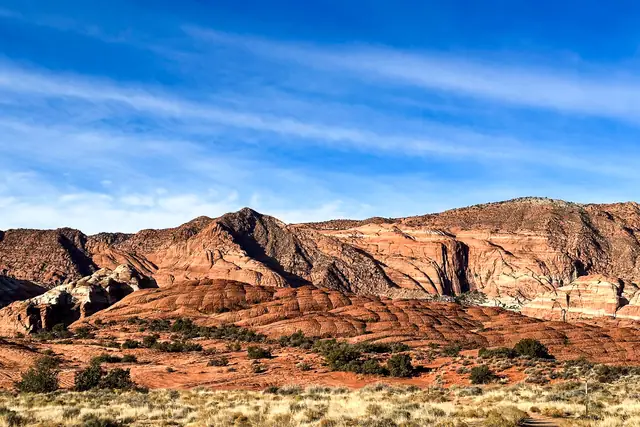 Morning light on red and white sandstone ridges above golden grass, Snow Canyon State Park.