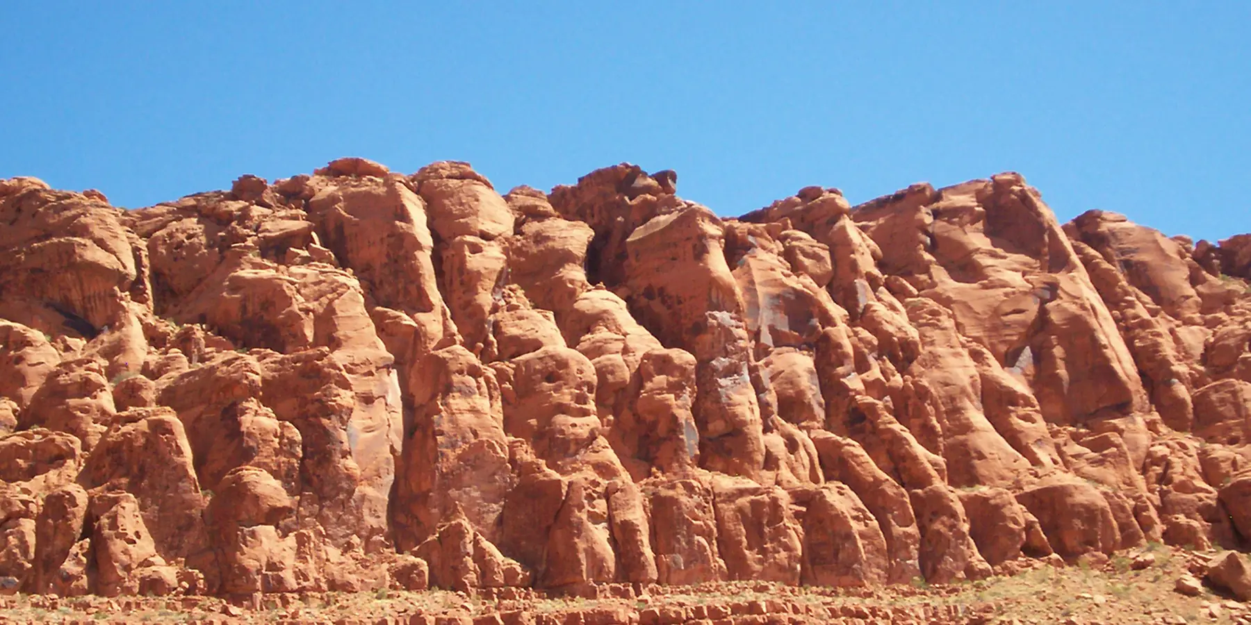 A wall of rounded red Navajo Sandstone formations under a blue sky in Snow Canyon State Park.