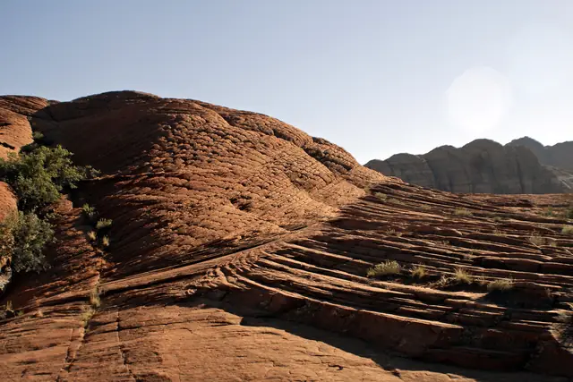 Layered red sandstone slickrock with sweeping wind-laid lines in evening light, Snow Canyon State Park.