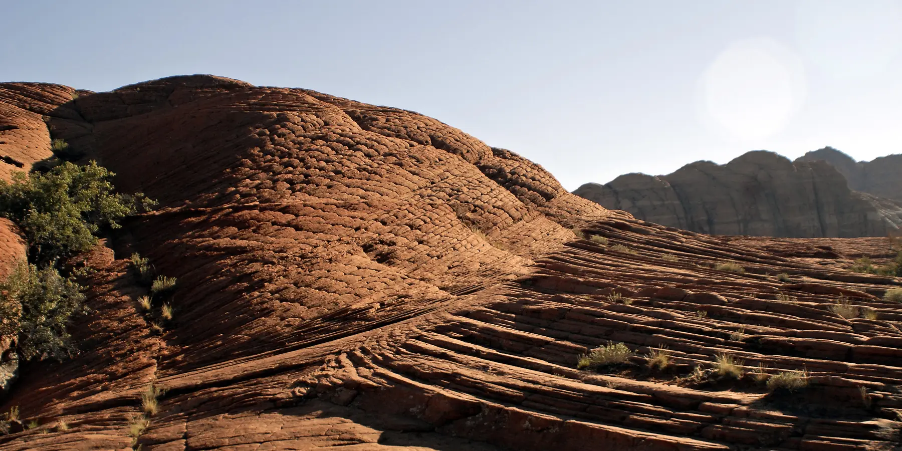 Layered red sandstone slickrock with sweeping wind-laid lines in evening light, Snow Canyon State Park.