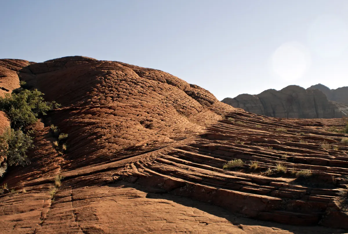 Layered red sandstone slickrock with sweeping wind-laid lines in evening light, Snow Canyon State Park.