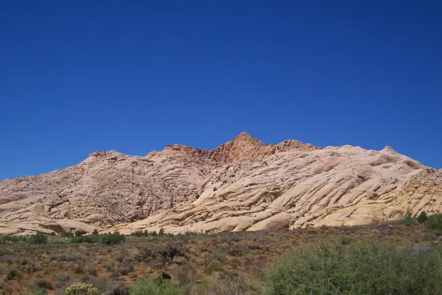 A long ridge of white Navajo Sandstone above desert scrub in Snow Canyon State Park.